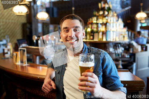 Image of happy man drinking draft beer at bar or pub