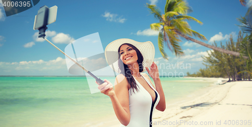 Image of happy woman taking selfie with smartphone on beach