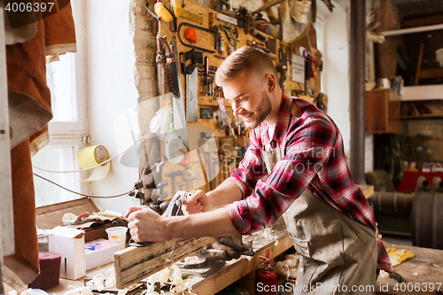 Image of carpenter working with plane and wood at workshop