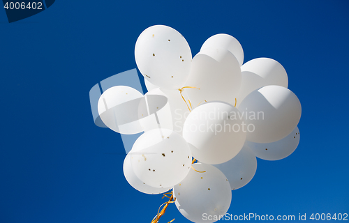 Image of close up of white helium balloons in blue sky