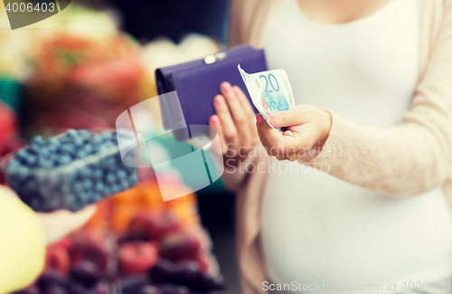 Image of pregnant woman with wallet buying beries at market