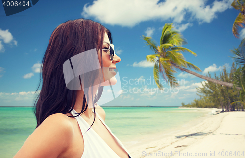 Image of smiling young woman with sunglasses on beach