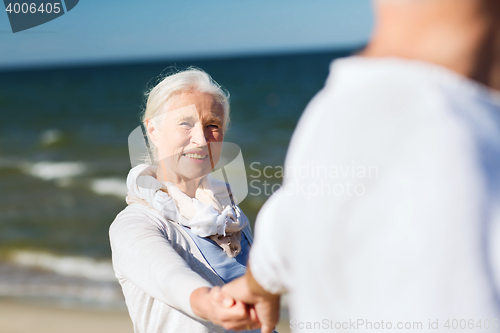 Image of happy senior couple holding hands on summer beach