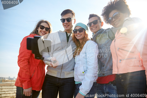 Image of smiling friends taking selfie with smartphone