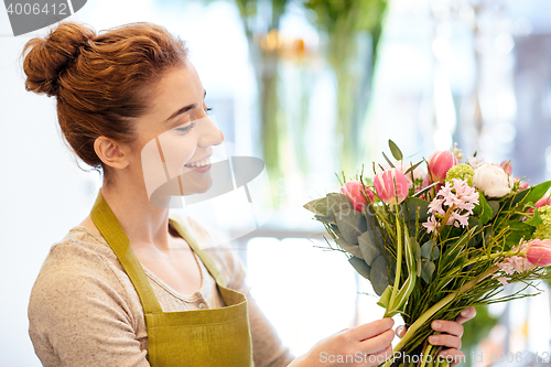 Image of smiling florist woman making bunch at flower shop