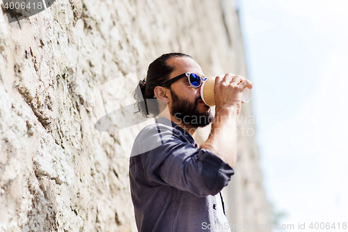 Image of man drinking coffee from paper cup on street