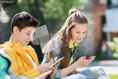 Image of happy teenage friends with gadgets outdoors