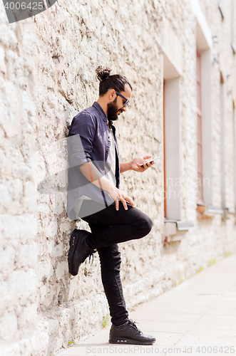 Image of man texting message on smartphone at stone wall