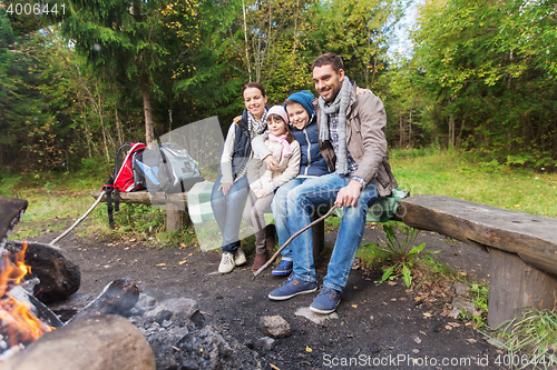 Image of happy family sitting on bench at camp fire