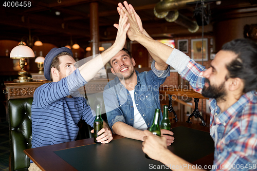 Image of men with beer making high five at bar or pub
