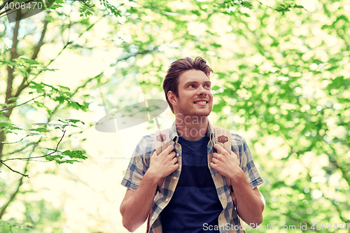 Image of smiling young man with backpack hiking in woods