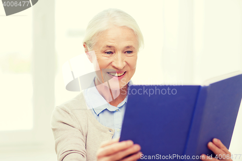 Image of happy smiling senior woman reading book at home