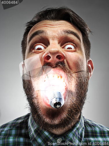 Image of Caucasian man with bulb in his mouth on gray background