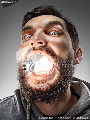 Image of Caucasian man with bulb in his mouth on gray background