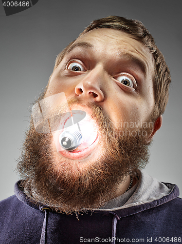 Image of Caucasian man with bulb in his mouth on gray background