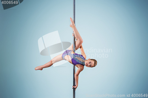 Image of The strong and graceful young girl performing acrobatic exercises on pylon