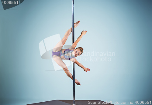 Image of The strong and graceful young girl performing acrobatic exercises on pylon