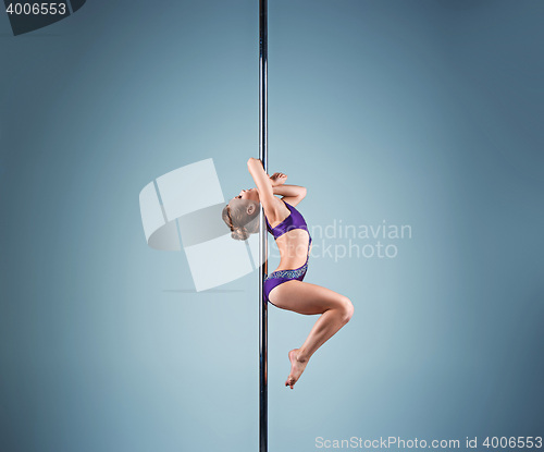 Image of The strong and graceful young girl performing acrobatic exercises on pylon