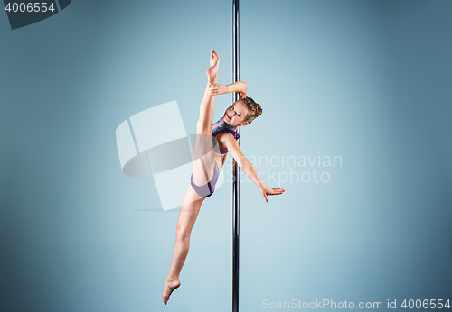 Image of The strong and graceful young girl performing acrobatic exercises on pylon