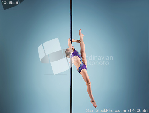 Image of The strong and graceful young girl performing acrobatic exercises on pylon