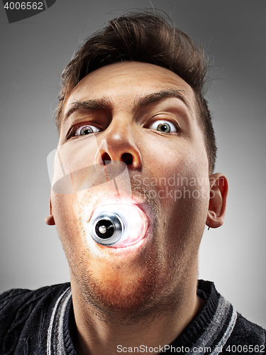 Image of Caucasian man with bulb in his mouth on gray background