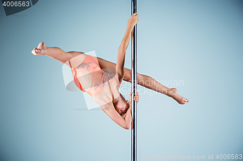 Image of The strong and graceful young girl performing acrobatic exercises on pylon