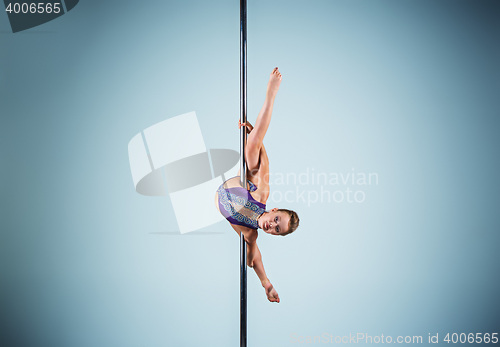 Image of The strong and graceful young girl performing acrobatic exercises on pylon