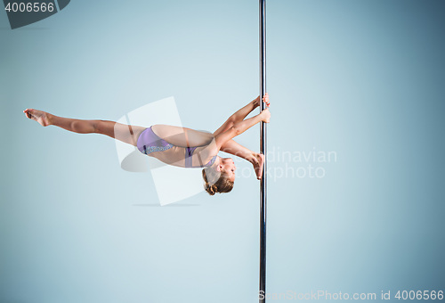 Image of The strong and graceful young girl performing acrobatic exercises on pylon