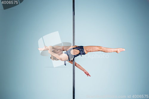 Image of The strong and graceful young girl performing acrobatic exercises on pylon