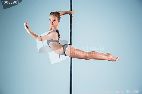 Image of The strong and graceful young girl performing acrobatic exercises on pylon