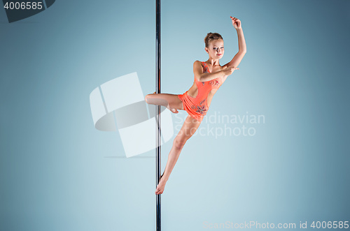 Image of The strong and graceful young girl performing acrobatic exercises on pylon