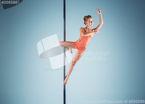 Image of The strong and graceful young girl performing acrobatic exercises on pylon