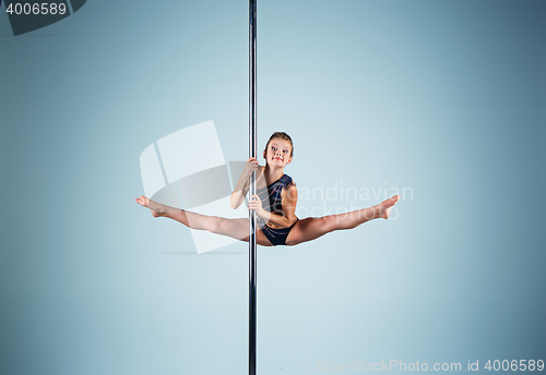 Image of The strong and graceful young girl performing acrobatic exercises on pylon