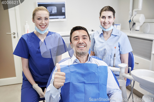 Image of happy female dentists with man patient at clinic