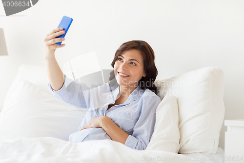 Image of pregnant woman taking smartphone selfie at home