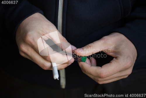 Image of close up of addict hands with marijuana joint tube