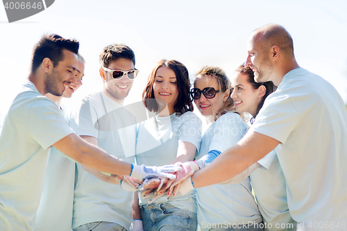 Image of group of volunteers putting hands on top in park