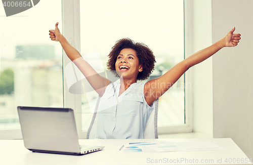 Image of happy african woman with laptop at office