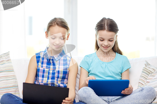 Image of happy girls with tablet pc sitting on sofa at home