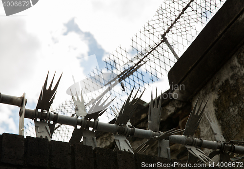 Image of close up of fence with barbed wire and mesh