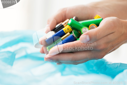 Image of close up of hands putting batteries to rubbish bag