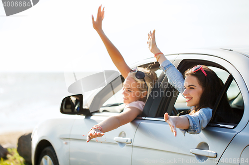 Image of happy teenage girls or women in car at seaside