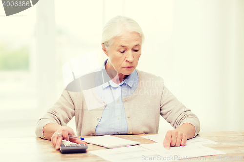 Image of senior woman with papers and calculator at home