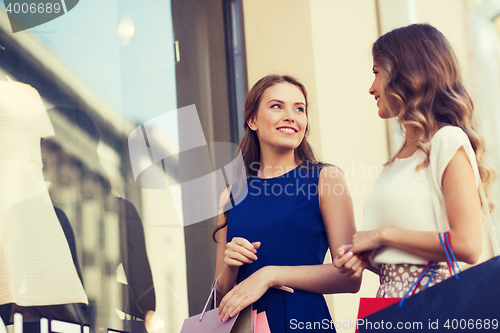 Image of happy women with shopping bags at shop window