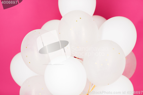 Image of close up of white helium balloons over pink