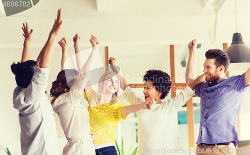 Image of happy creative team celebrating victory in office