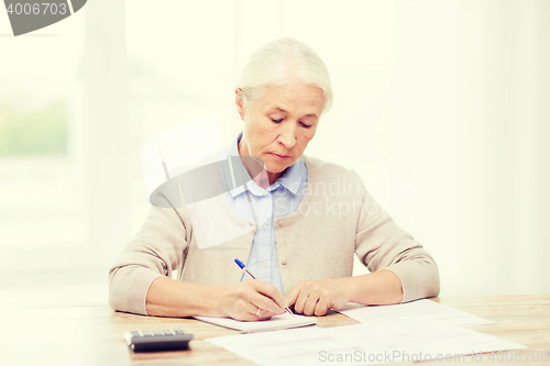 Image of senior woman with papers and calculator at home