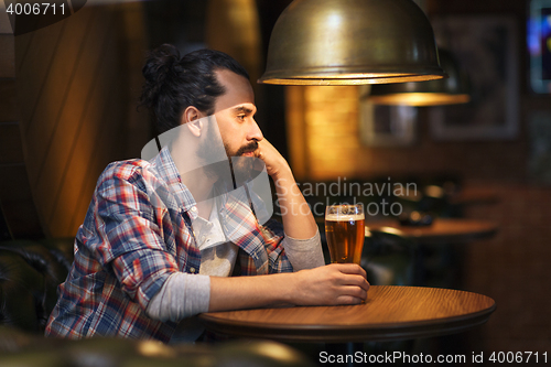 Image of unhappy lonely man drinking beer at bar or pub