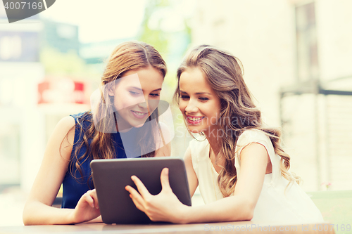 Image of happy young women with tablet pc at outdoor cafe