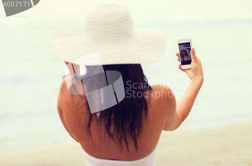 Image of smiling young woman taking selfie with smartphone